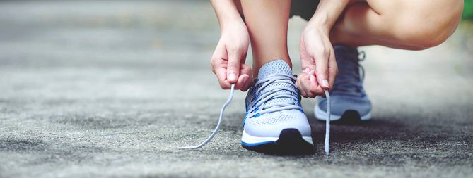 Frau schnürt Sportschuhe